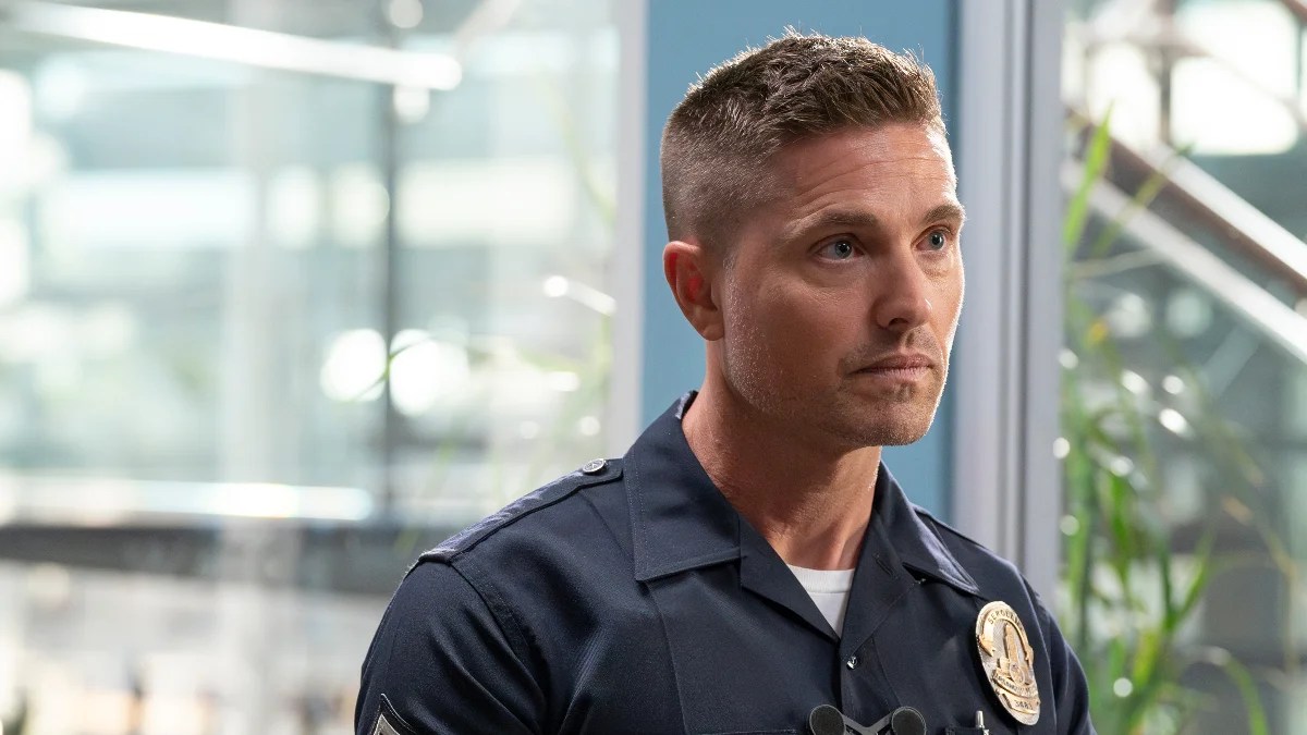 A tan police officer in uniform looks right of frame